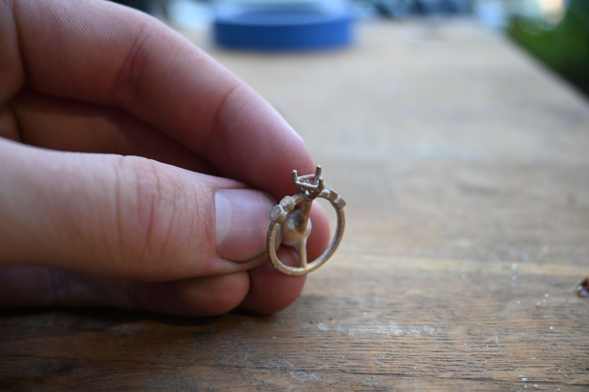 A freshly cast gold ring held beside its sprue